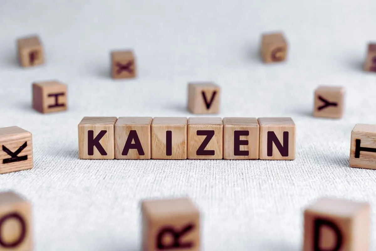 Cubes en bois avec mot "Kaizen" sur fond textile.