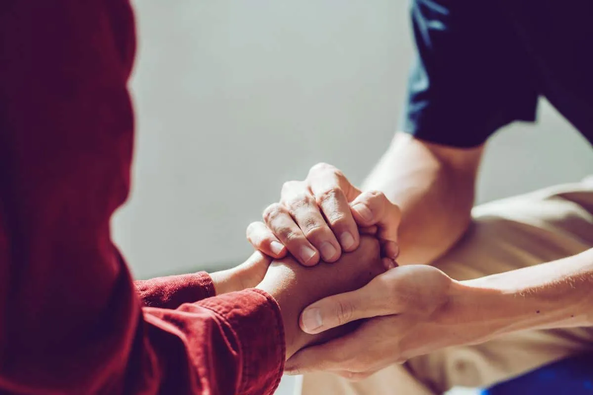 Deux personnes se tenant les mains en signe de soutien.
