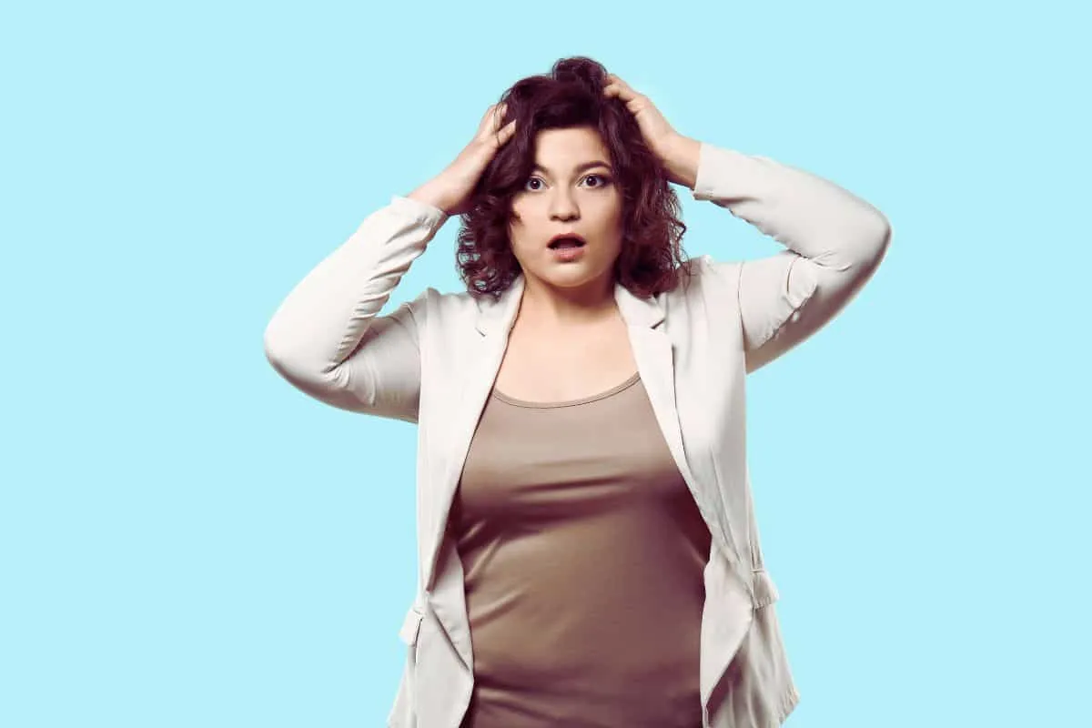 Femme surprise avec mains sur la tête.