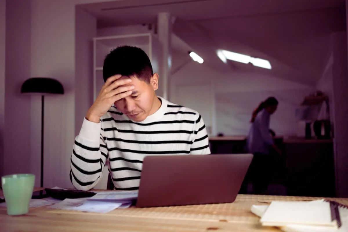 Homme stressé travaillant sur ordinateur.